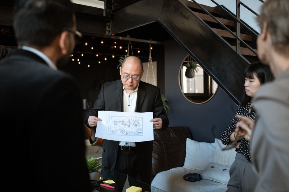 A diverse business team discussing a blueprint in a stylish and modern office setting.
