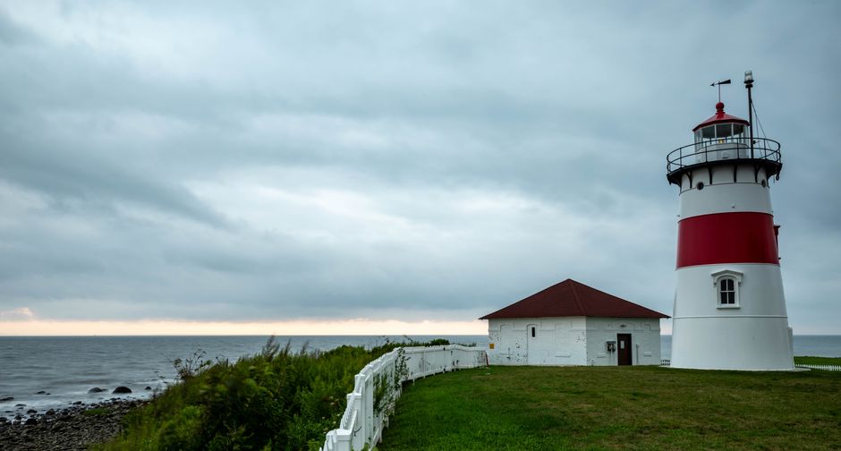 Lighthouse by the ocean with dramatic cloudy sky, capturing coastal beauty and maritime safety.